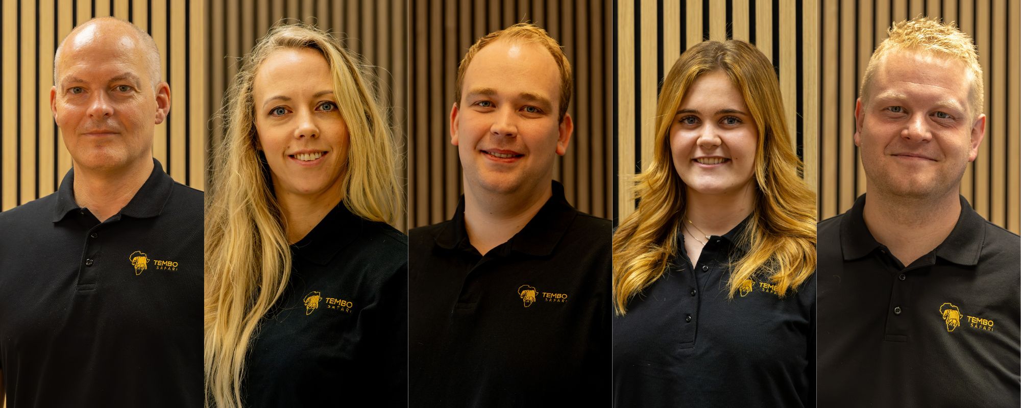 Group portrait of five staff members in black polo shirts with Tembo Safari logo, posing in front of wooden panel backdrop. They are smiling at the camera.